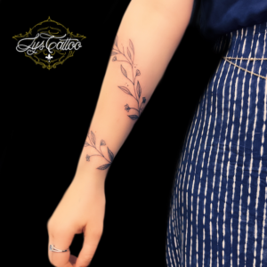 Tatouage autour du bras, femme, composition d’une belle liane florale et feuillage, tout en finesse. Création par les plus bons tatoueurs de Bordeaux à Gradignan proche de Andernos les Bains et Le Haillan en Gironde.