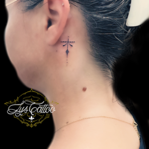 Tatouage derrière l’oreille, femme, petite,croix minimaliste customiséee et féminisée. Tatouage réalisé dans le meilleur salon de tatouage de Bordeaux à Villenave d’or on, proche de Libourne et Eysines en Gironde.
