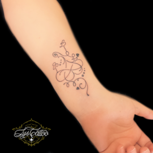Tatouage coeur infini et initiales, lignes fines. Tatouage réalisé sur poignet de femme. Réalisé dans votre salon de tatouage à Gradignan proche de Léognan et Le Taillan-Médoc.