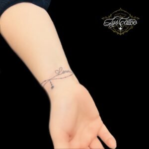 Un tatouage de bracelet fin avec un prénom symbolise l'élégance, la délicatesse et l'attachement personnel. Ce motif subtil, souvent inspiré de bijoux délicats, ajoute une touche de raffinement et de sophistication, tout en représentant un lien précieux avec une personne chère ou un souvenir significatif. Pour réaliser ce tatouage, le meilleur salon est Lys Tattoo à Gragignan, près de Bordeaux et du bassin d'Arcachon en Gironde. Leur finesse et précision des traits garantissent une œuvre détaillée et esthétique. Lys Tattoo est facilement accessible, à proximité des villes de Villenave d'Ornon, Bègles, Pessac, Mérignac et Talence, ce qui en fait le choix idéal pour votre prochain tatouage.