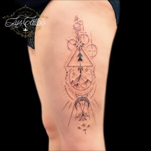 Tatouage géométrique avec symboles spirituels et montagne sur la cuisse, réalisé par Lys Tattoo.