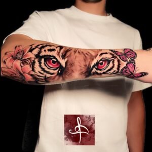 Tatouage réaliste d'yeux de tigre avec papillons et fleur de lys sur l'avant-bras, réalisé par Rhum1 Tattoo.