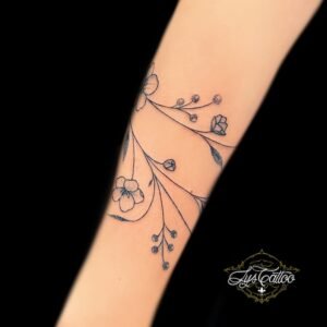 Tatouage floral délicat en noir et gris sur l’avant-bras, réalisé par Lys Tattoo à Villenave d’Ornon, proche de Bordeaux, Pessac et Talence.