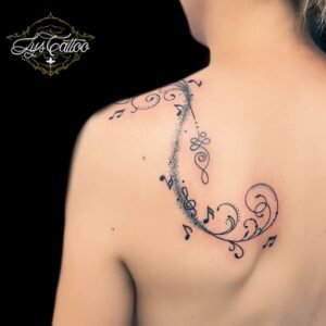 Tatouage ornemental musical sur l’omoplate, intégrant des notes de musique et des arabesques, réalisé en dotwork par Lys Tattoo à Gradignan, près de Bordeaux et Pessac.