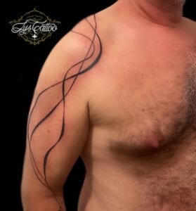 Tatouage abstrait minimaliste aux lignes fluides parcourant l’épaule et le bras, réalisé par Lys Tattoo au salon Lys Tattoo à Gradignan, bientôt à Villenave d'Ornon, proche de Bordeaux, Pessac et Talence.