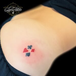 Tatouage minimaliste des quatre symboles de cartes à jouer sur la hanche, réalisé par Lys Tattoo au salon Lys Tattoo à Gradignan, bientôt à Villenave d'Ornon, proche de Bordeaux, Pessac et Talence.