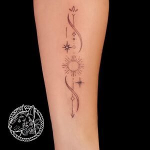 Tatouage minimaliste sur l'avant-bras représentant un soleil entouré d’étoiles et de motifs géométriques, réalisé par Le Bull Tatoué chez Lys Tattoo.