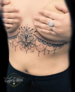 Tatouage ornemental sous-poitrine représentant un lotus finement détaillé avec des motifs mandala et des ornements en guirlande, réalisé par Lys Tattoo au salon Lys Tattoo à Gradignan, près de Bordeaux.