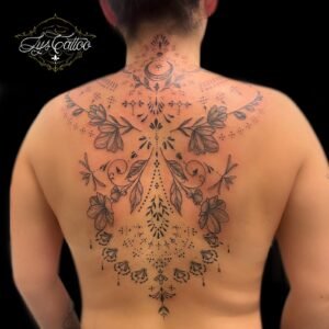 Tatouage ornemental et floral sur le dos, combinant des motifs floraux délicats, des arabesques et une lune mystique, réalisé par Lys Tattoo au salon Lys Tattoo à Gradignan, près de Bordeaux.