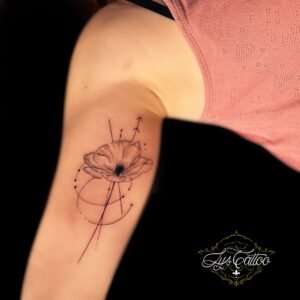 Tatouage fin et élégant d’un coquelicot géométrique agrémenté de flèches et de lignes dynamiques, réalisé par Lys Tattoo du salon Lys Tattoo à Gradignan, près de Bordeaux.