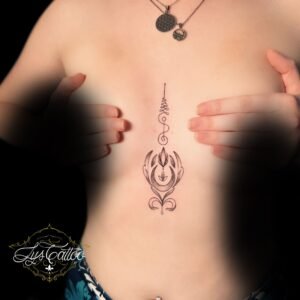 Tatouage ornemental minimaliste situé entre les seins, avec des motifs géométriques et floraux délicats, réalisé en fine ligne par Lys Tattoo à Gradignan (Bordeaux).