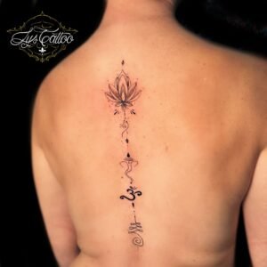 Tatouage minimaliste dans le dos, avec un motif de lotus et des symboles spirituels, réalisé en fine ligne par Lys Tattoo à Gradignan (Bordeaux).