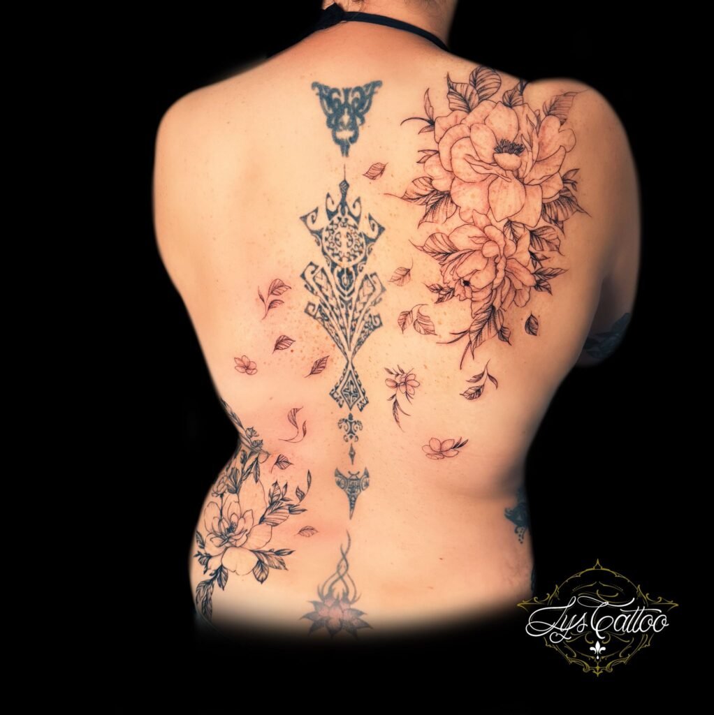 Tatouage floral et ornemental sur le dos, combinant des motifs géométriques complexes et des fleurs délicates en noir et gris, réalisé par Lys Tattoo à Gradignan (Bordeaux).