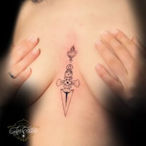 Tatouage symbolique en noir représentant un poignard avec un cœur enflammé sur le sternum, réalisé par Lys Tattoo chez Lys Tattoo à Gradignan (Bordeaux)