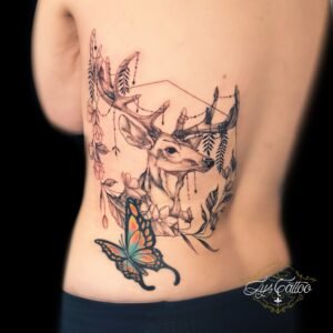 Tatouage de cerf ornemental en noir avec papillon coloré sur le dos, réalisé par Lys Tattoo chez Lys Tattoo à Gradignan (Bordeaux)