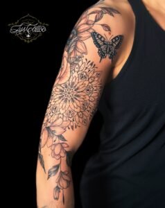 Tatouage manchette florale et mandala en noir avec papillon sur le bras, réalisé par Lys Tattoo chez Lys Tattoo à Gradignan (Bordeaux)