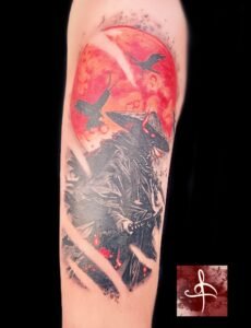 Tatouage sombre et détaillé représentant un chasseur masqué sous une lune rouge sang, accompagné de corbeaux, réalisé par Rhum1 Tattoo au Lys Tattoo.