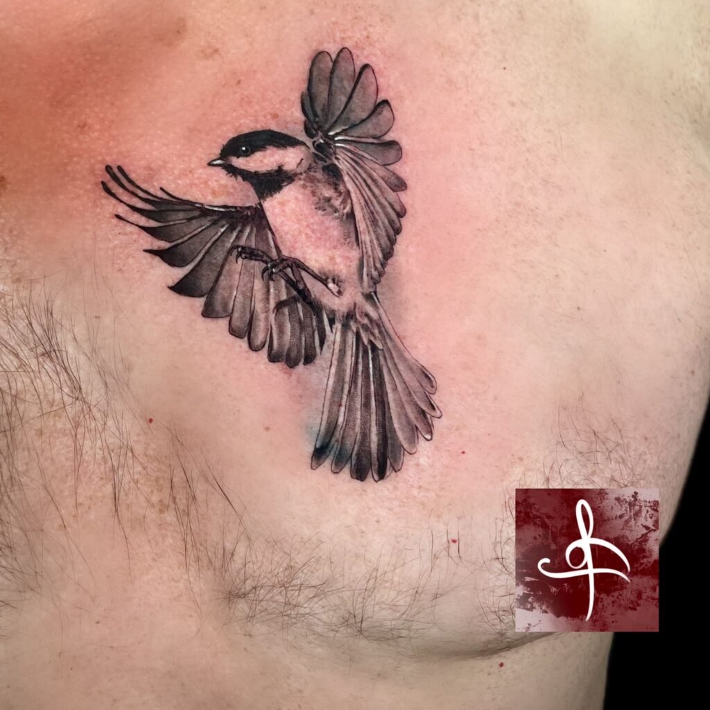 Tatouage réaliste d'une mésange en plein vol, conçu par Rhum1 Tattoo au salon Lys Tattoo.