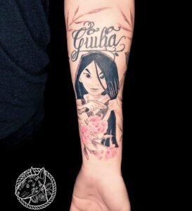 Tatouage portrait de Mulan avec fleurs roses et prénom Giulia sur l’avant-bras, réalisé par Le Bull Tatoué au salon Lys Tattoo.