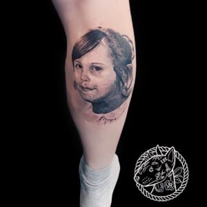 Tatouage réaliste de portrait d'enfant sur le mollet, réalisé par Le Bull Tatoué au salon Lys Tattoo.