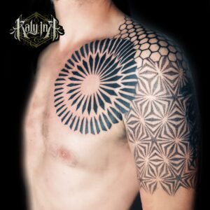 Tatouage poitrine-épaule blackwork, grande rosace rayonnante et alvéoles géométriques – Kaly Ink Bordeaux