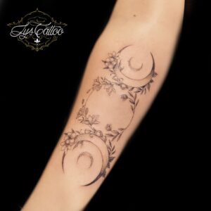 Tatouage double lune et fleurs en fine line sur avant-bras – Lys Tattoo Bordeaux