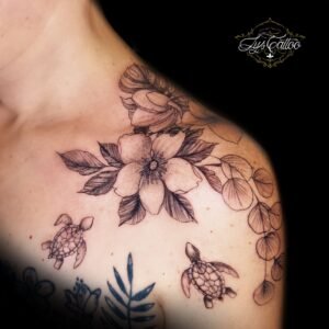 Tatouage épaule fleur et feuillage en fine line, tortues marines stylisées – Lys Tattoo Bordeaux