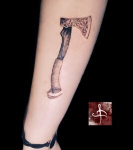 Tatouage hache viking en noir et gris, manche texturé et motifs nordiques – avant-bras