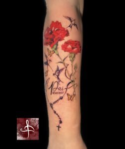 Tatouage avant-bras œillets rouges avec oiseaux, papillons, prénom et chapelet