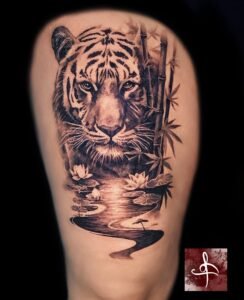 Tatouage tigre réaliste en noir et gris avec bambous et reflet d’eau sur la cuisse