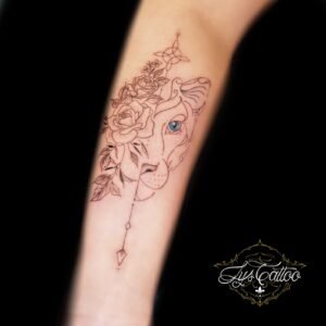 Tatouage lionne florale œil bleu en fine line sur l’avant-bras