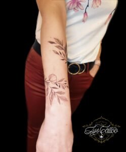 Tatouage branche et petite fleur en ligne fine sur le poignet