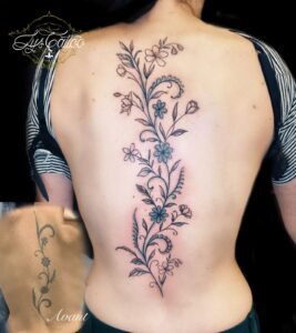 Refonte d’un tatouage vertical floral sur le dos avec avant/après