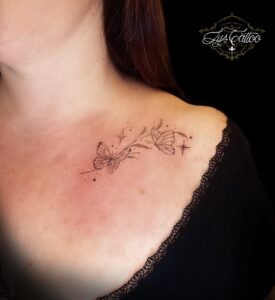 Tatouage papillons et étoiles en ligne fine près de la clavicule