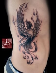 Tatouage phénix noir et gris sur flanc, flammes et mouvement – Rhum1 Tattoo Bordeaux