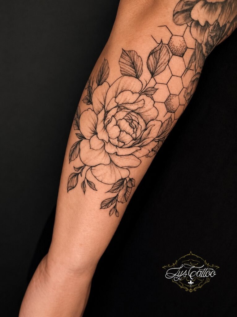 Tatouage floral noir et gris représentant une grande pivoine avec motif alvéoles sur l’avant-bras, réalisé chez Lys Tattoo à Villenave-d’Ornon.